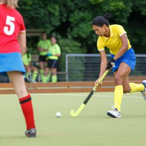 Field hockey female player leading the ball in attack. Young woman playing in field hockey tournament
