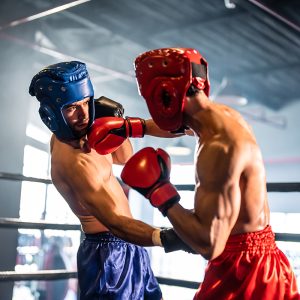 Two young professional boxer having a competition tournament on stage. Attractive male athlete fighters muscular shirtless punches and hitting competitor enjoy boxing exercise in the ring at stadium.